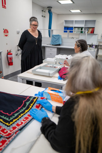 three people grouped around a collection of colourful garments