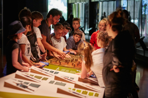 Primary school students participating in the 'Our Shared History' program all gathered around welcome table.