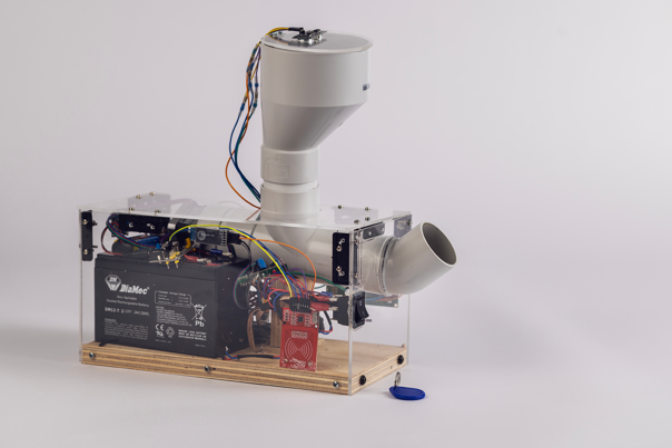 Chicken feeder with a clear acrylic casing, grey PVC pipes, electronic components, and a battery.