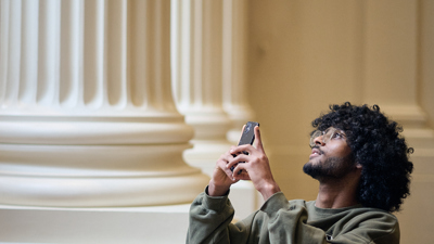 A young man taking a photo in the Long Room at the Immigration Museum