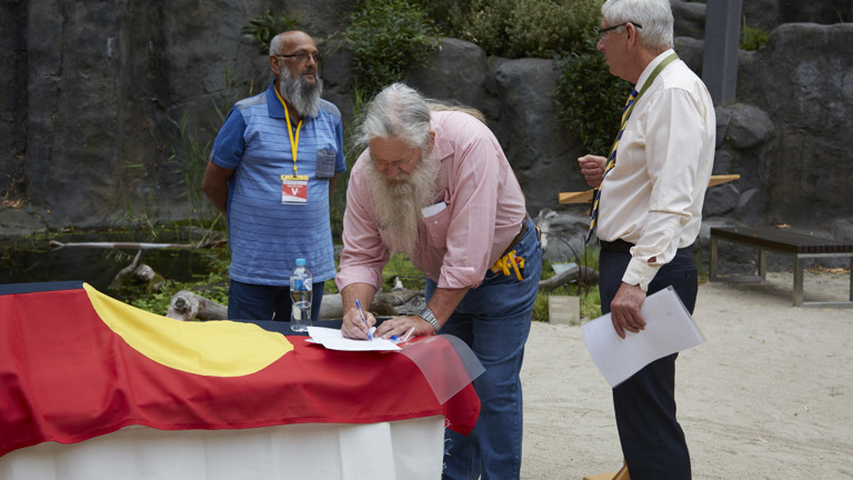 Three men signing papers