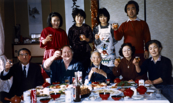 Family gathered around a table laid food.