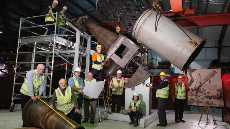 Group of people in high-vis vests standing by a large telescope