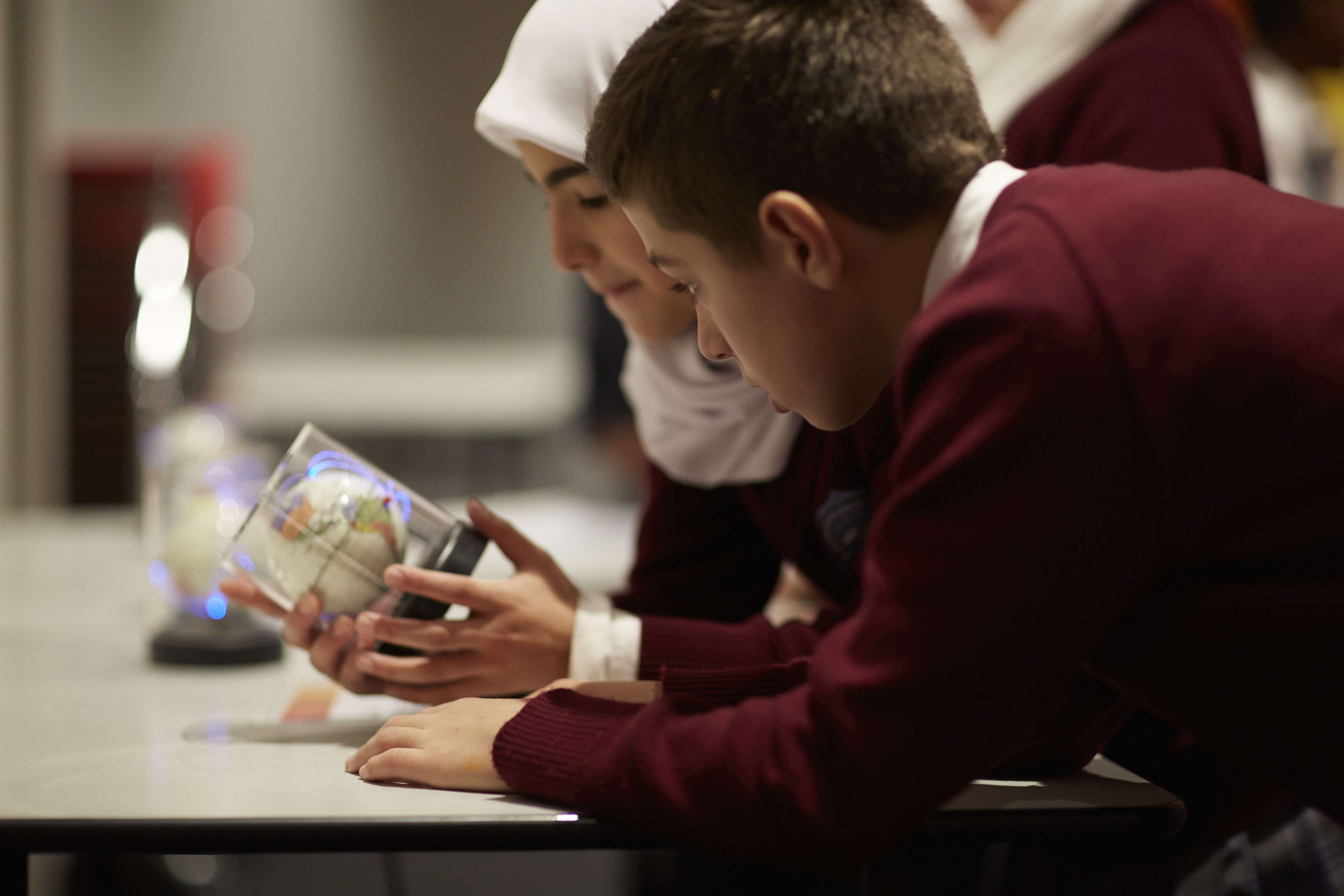 Girl and boy looking at a small globe