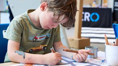 Child with craft materials and road maps at the activity, lower ground floor outside the Learning studios.