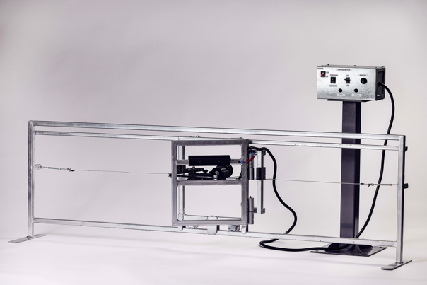 Miniature fence and gate made of metal bars, wires, and a control box mounted on a stand.