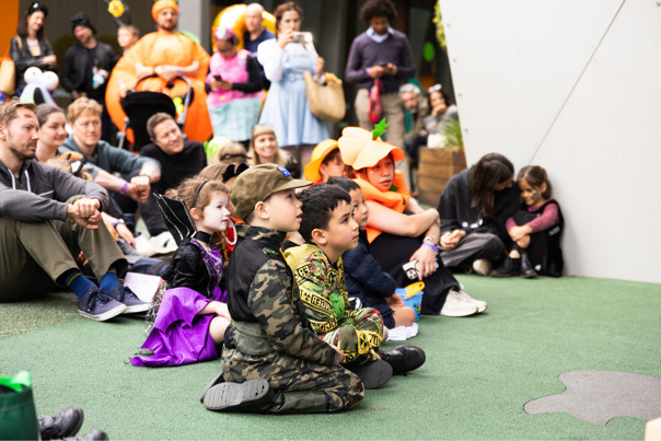 Families dressed in Halloween costumes learn about spooky science at a science show during Halloween at the Museum.