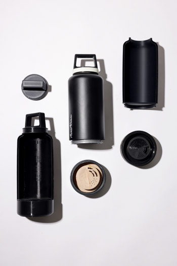 Flat lay of a matte black water bottle with screw top lid and removable base, bisected to show its main internal compartment.