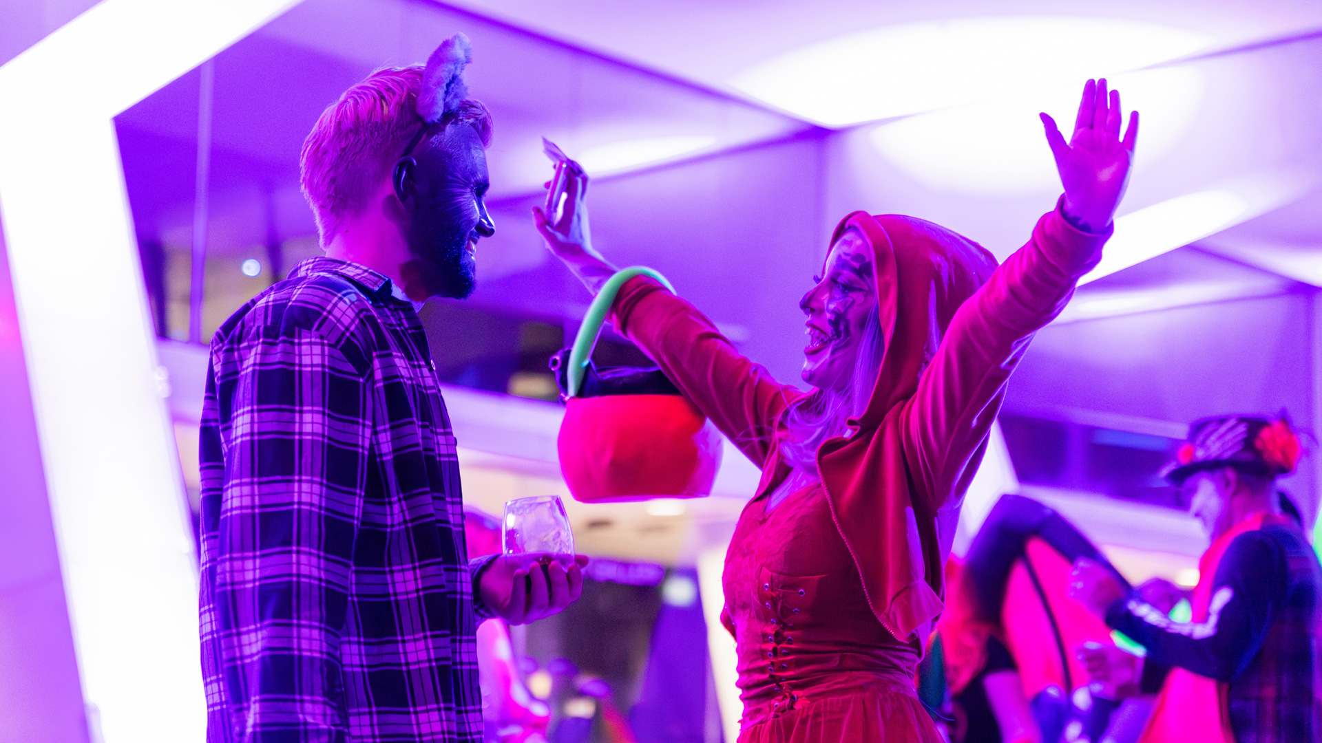 Two people in fancy dress. The lighting has a pink hue