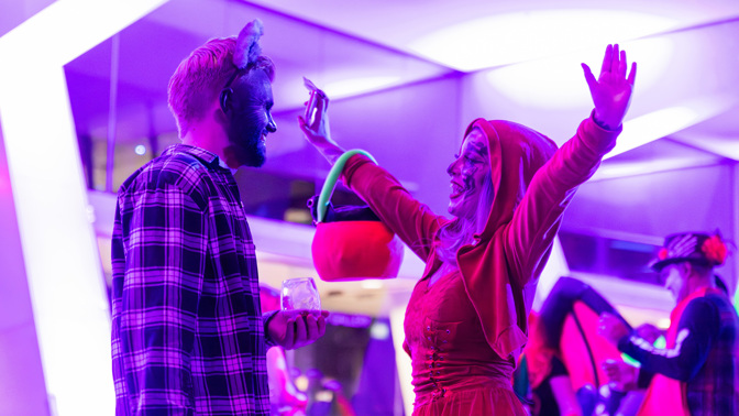 Two people in fancy dress. The lighting has a pink hue