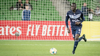 Football player Thomas Deng chasing the ball on the field.