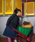 A child using a wheelbarrow to move bricks