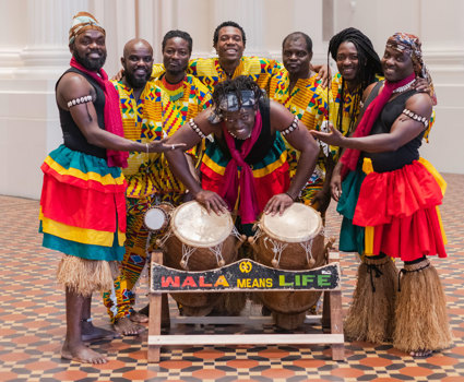 WALA Drum & Dance Ensemble in the Long Room of the immigration Museum posing with their drums.