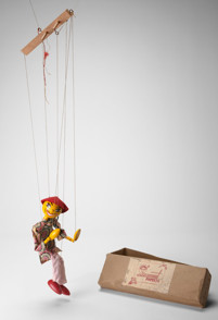 Wooden puppet dressed in a flower print tunic, light pink pants, red felt hat and a plaited ponytail
