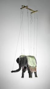 Elephant covered in grey cloth wearing a green fringed rug, edged with silver sequins