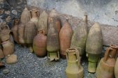 A dozen two-handled stone jars leaning on a wall 