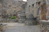 Two stone mill stones - one is enclosed and the other is shaped like a funnel and hollow with a rectangular slot
