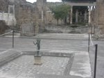 Bronze statue of a dancing faun in the foreground; north of the dancing faun is a roped-off mosaic floor surrounded by columns