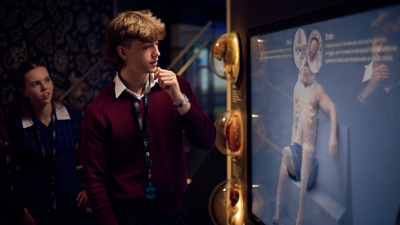 A student standing in front of a touch screen in the Road to Zero Experience Space looking at an image of the Graham sculpture 