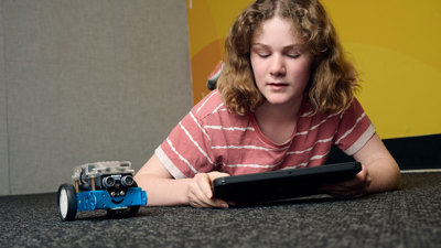A young adult programs their robot on an iPad during a Robots and Coding workshop at Scienceworks.