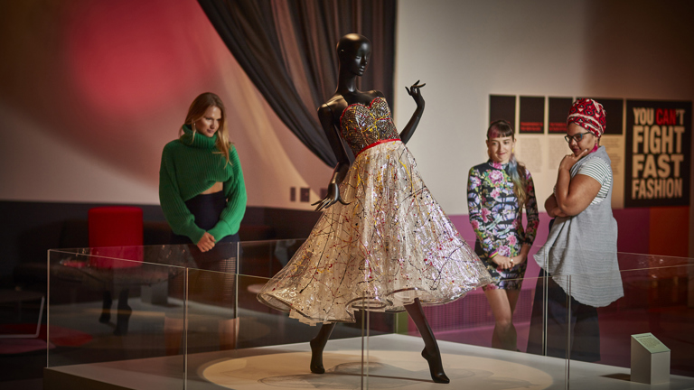 Three women looking at the Jenny Bannister 'Splash Plastic' dress on display in the 'You Can't Do That' exhibition at Melbourne Museum.