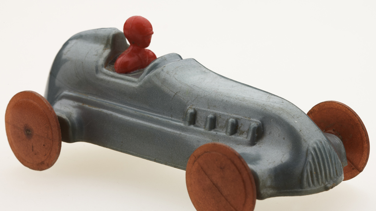 Grey car with orange wheels and red figure in driving seat.