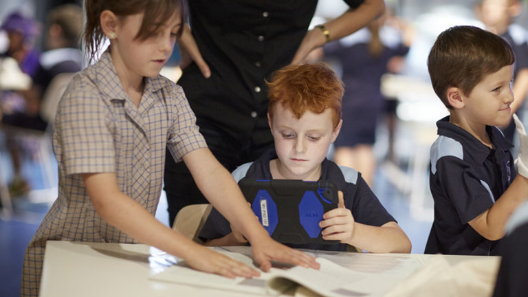 2 students using an iPad to take a photo of a book