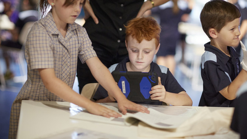 2 students using an iPad to take a photo of a book