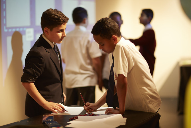 2 students standing by a table making notes