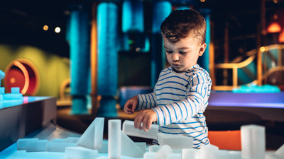 Boy playing with clear building blocks in the Ground Up exhibition 