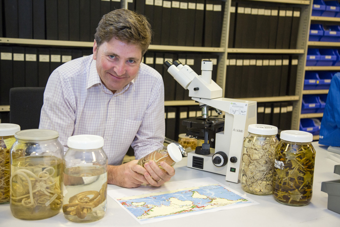 Dr. Tim O'Hara in Marine Vertebrate research laboratory holding a specimen jar containing Brittle Stars.