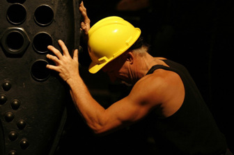 A worker poses with one of the historic boilers in the North Boiler House.