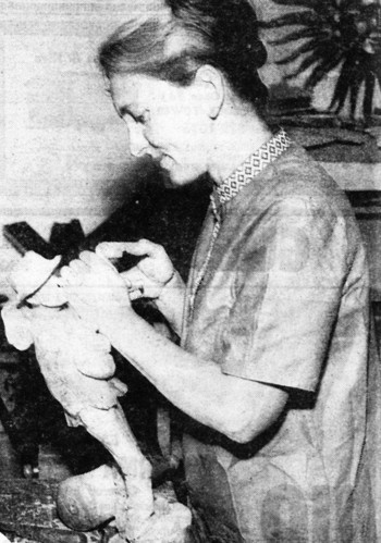 Black and white newspaper clipping of a woman carving wood