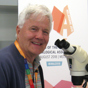 Man sitting in front of a microscope looking at the camera