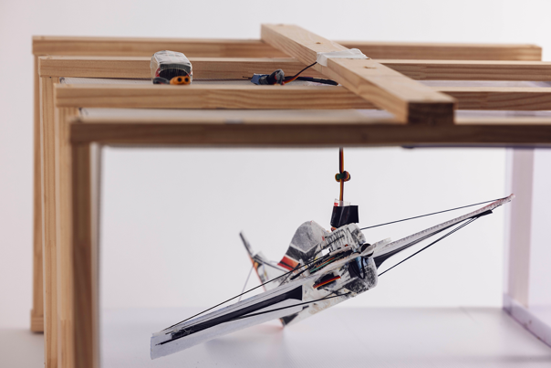 Model aeroplane suspended under a wooden frame with attached wiring and motors.
