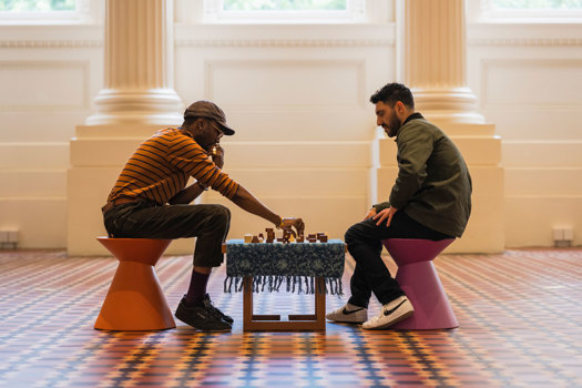 Maleik Njoroge playing chess in the Long Room of the Immigration Museum.