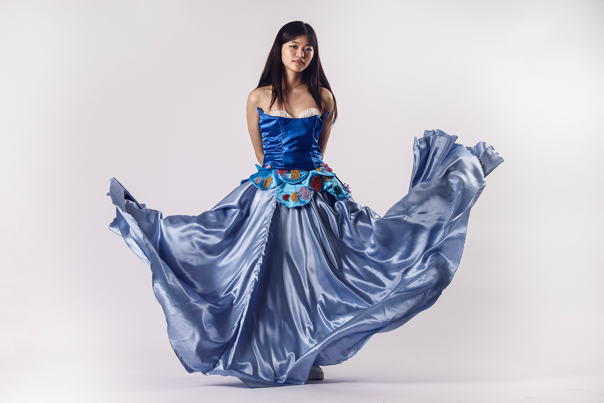 Person in a strapless blue satin gown with a structured bodice and embroidered floral details.