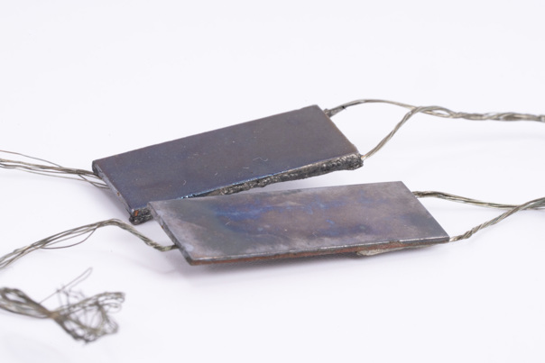 Flat metal objects with wires coming off the ends.