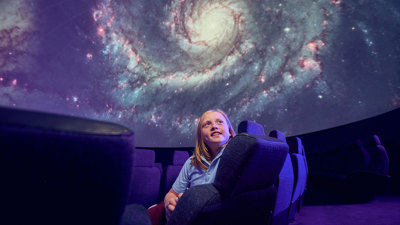 A Primary school student observes a projection of the stars on the dome of the Melbourne Planetarium 