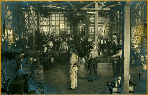 Interior of a large shed with many workers using different types of machinery