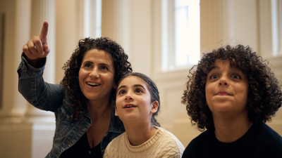A close-up on a young family looking at the Long Room at the Immigration Museum.