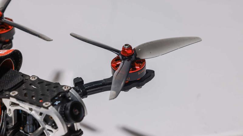 Close-up photo of a transparent black drone propeller with red-metal fixtures.