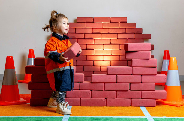 Small child next to brick-like building blocks and traffic cones
