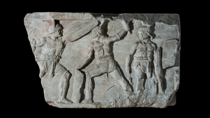 Image of an ancient Roman marble carving of three gladiators in a fighting pose with swords. 