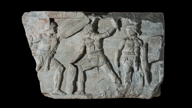Image of an ancient Roman marble carving of three gladiators in a fighting pose with swords. 