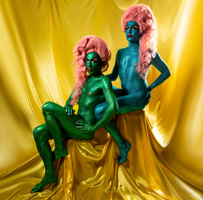 Artist bio shot of The Huxleys in a blue and green glittery body suits.