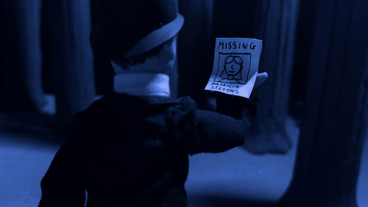 Stop-motion animation scene in dark blue tones showing a pir of hands holding a missing person flyer with a sketch of a person wearing glasses.