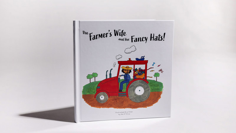 Picture book cover featuring a woman in overalls and a straw hat, driving a red tractor through a country landscape.