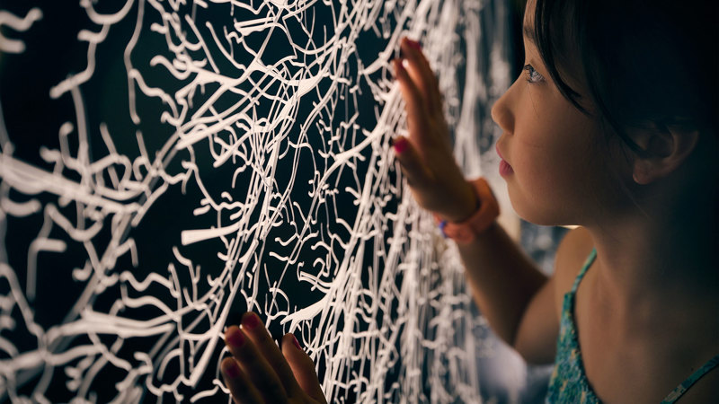 Close up of a young girl looking at a representation of a mycelium network.