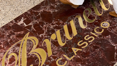 A person walking on a marble floor with Brunetti Classico embossed in gold letters.